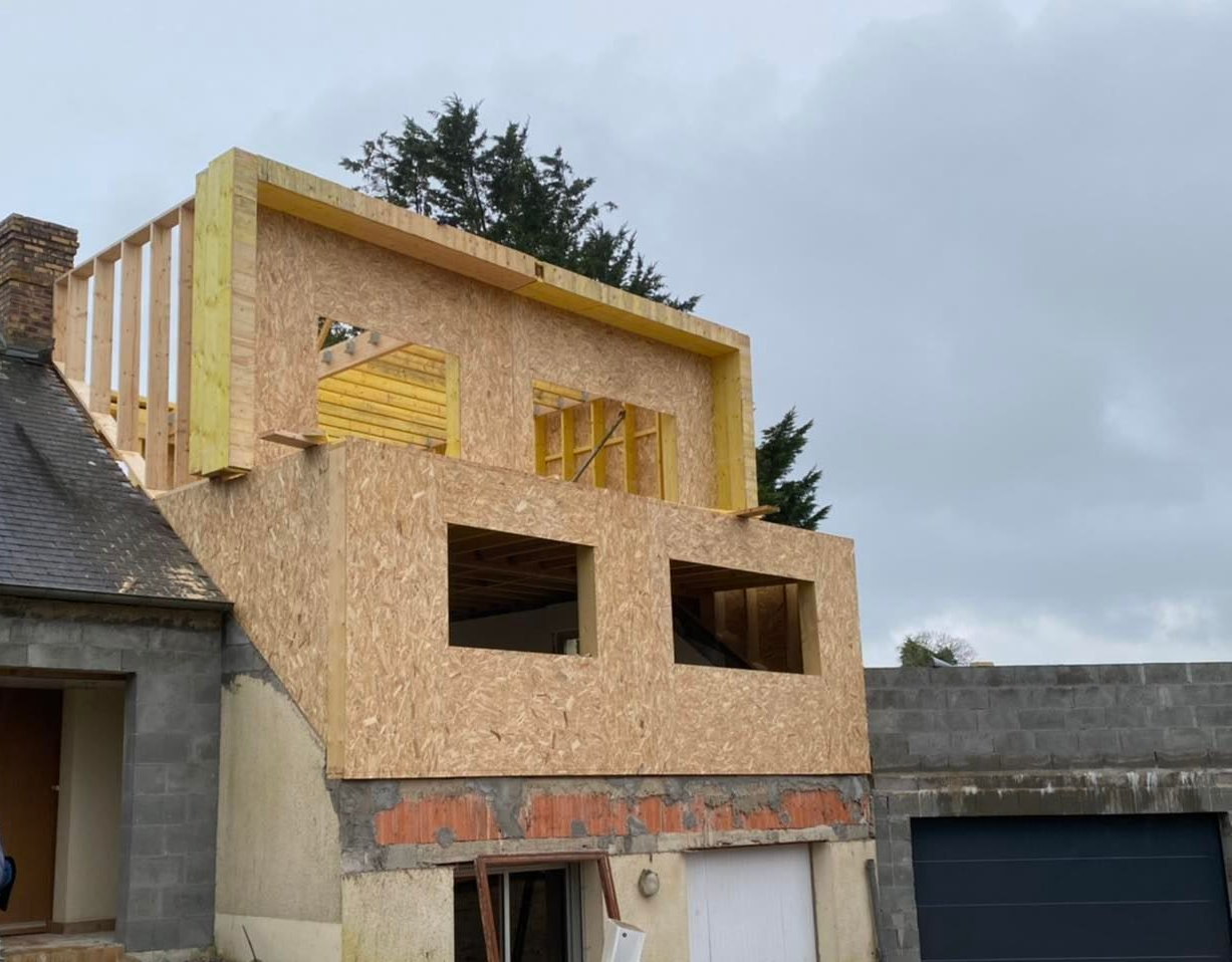 Travaux en cours sur une maison comportant une nouvelle extension en bois à l'étage.