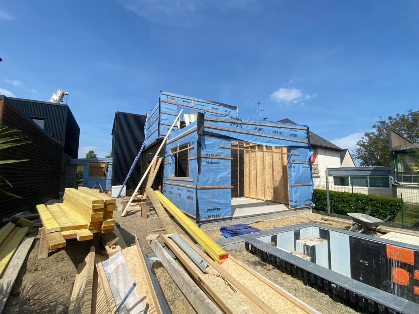 Un chantier de construction avec une maison à ossature bois partiellement construite.