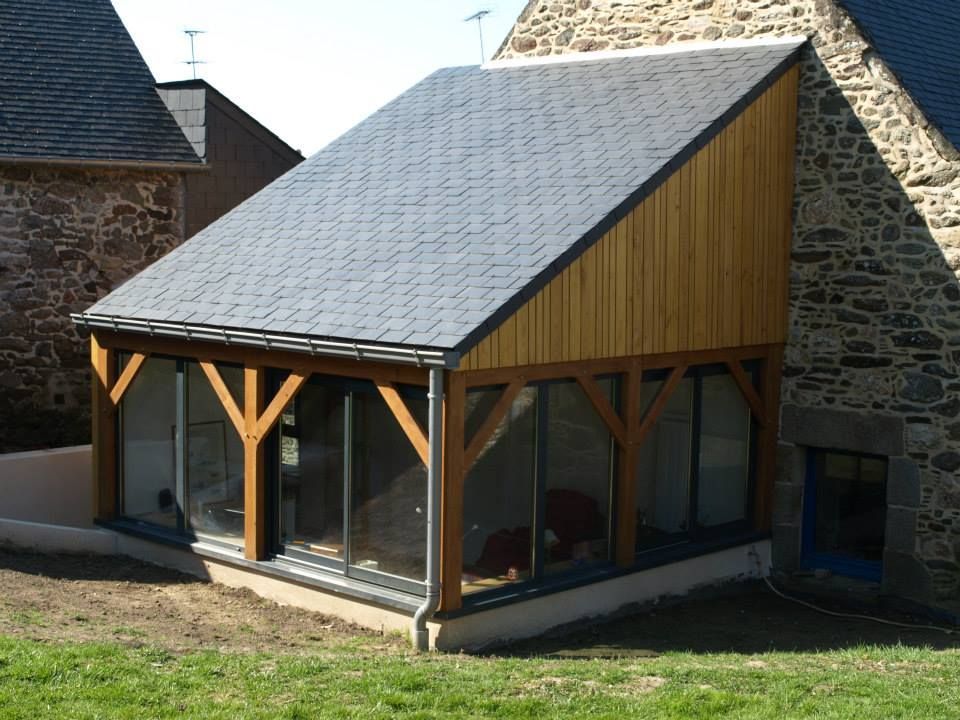 Une véranda à ossature bois, avec de grandes baies vitrées.