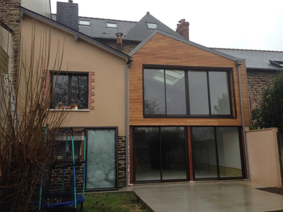 Une extension de maison avec un revêtement en bois et de grandes fenêtres.