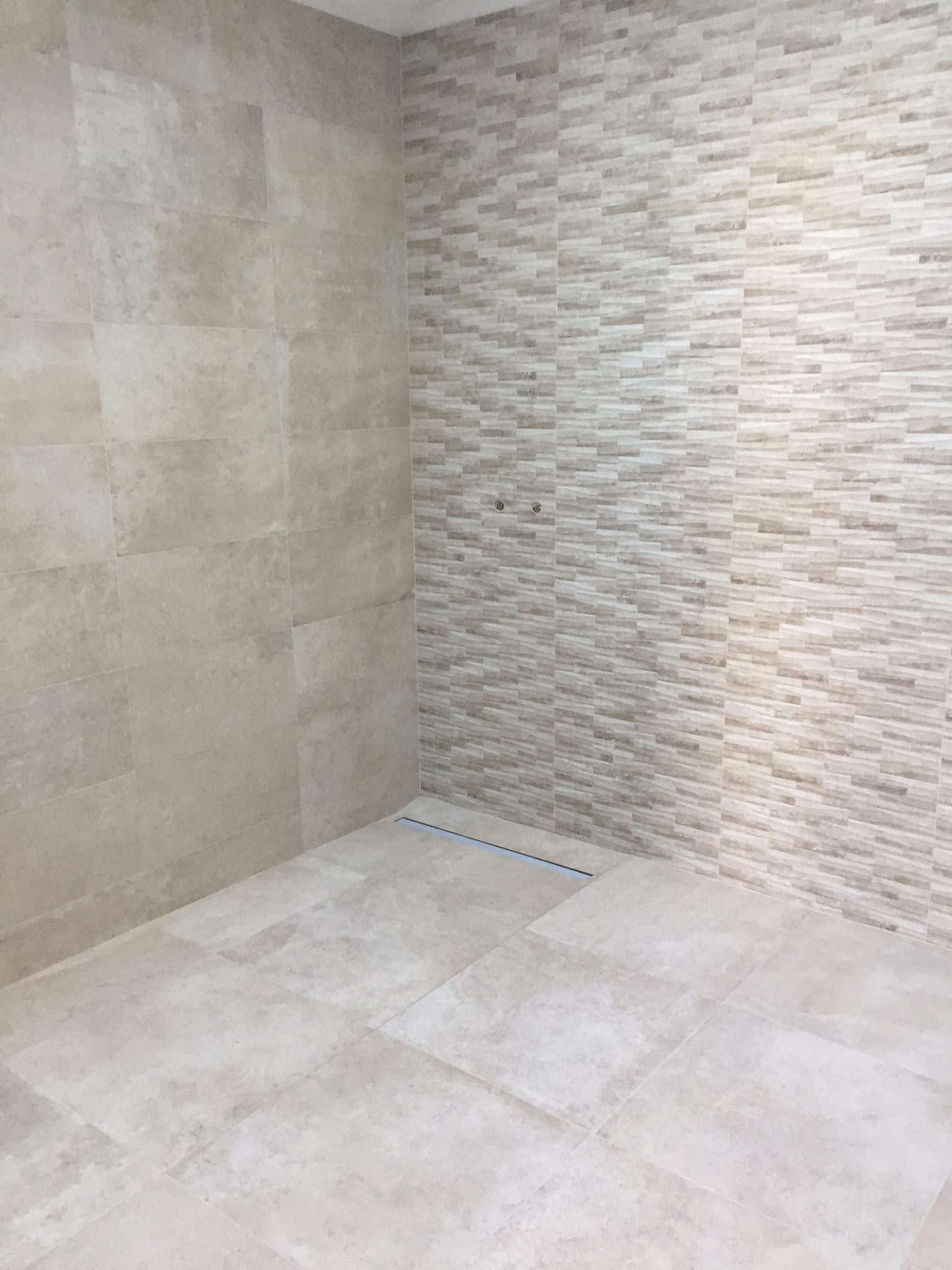 Salle de bains avec murs et sol carrelés.