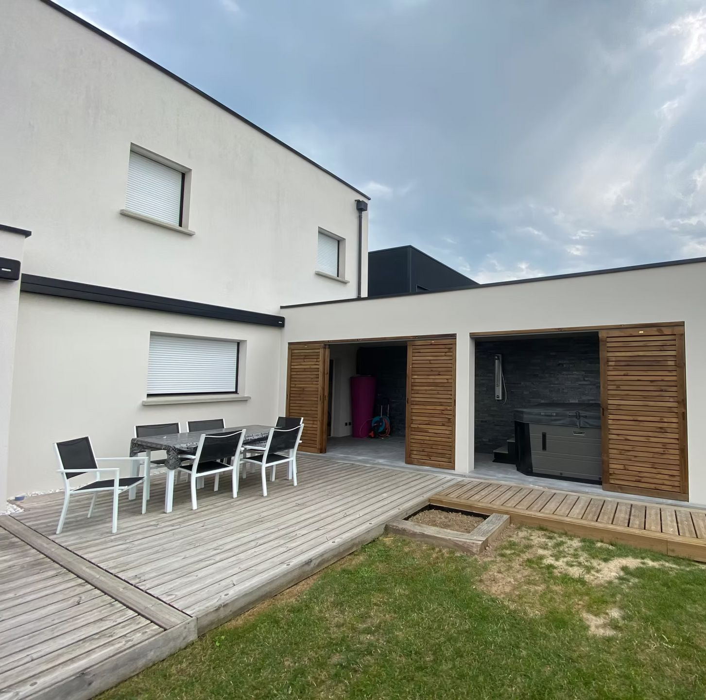 Une maison moderne blanche avec une terrasse en bois.