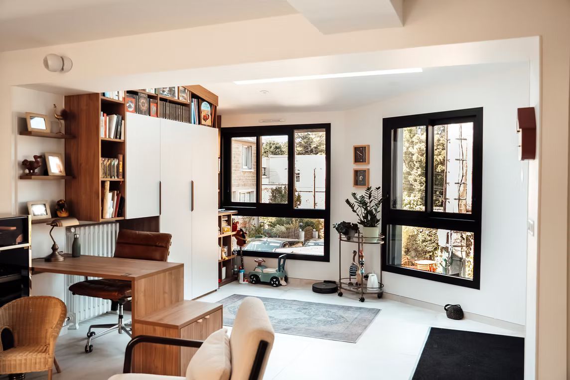 Un bureau lumineux, une bibliothèque et de grandes fenêtres donnant sur la verdure.