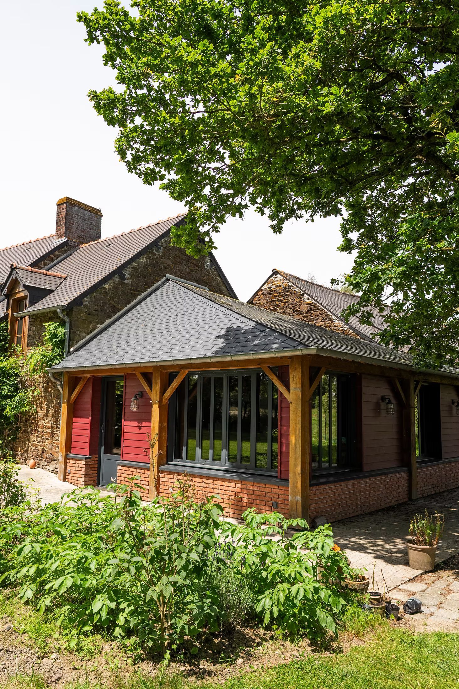 Une maison rustique en pierre avec une extension en briques à ossature bois.
