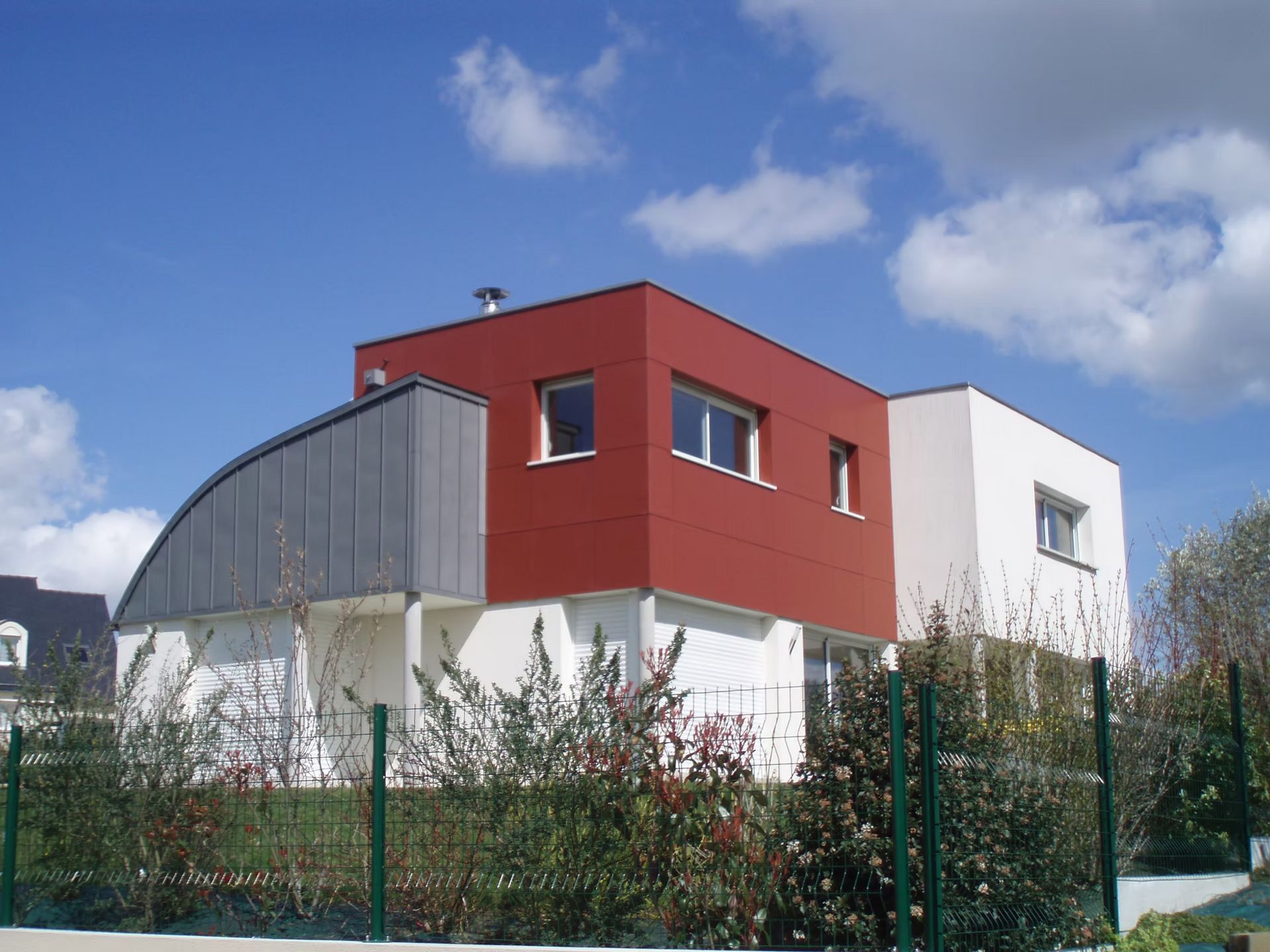 Un bâtiment avec une extension en bardage rouge.