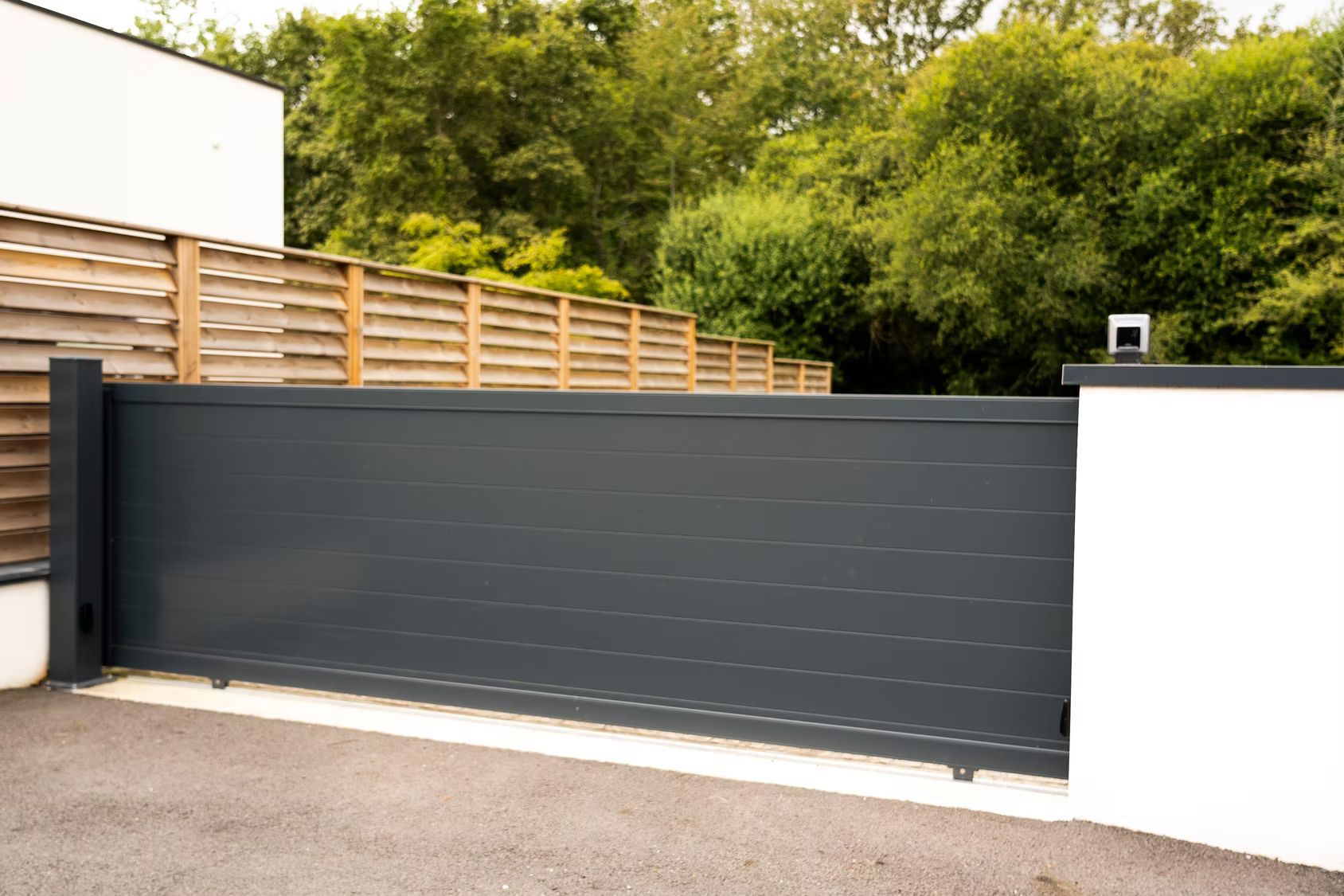 Un portail coulissant moderne à lames horizontales gris foncé.