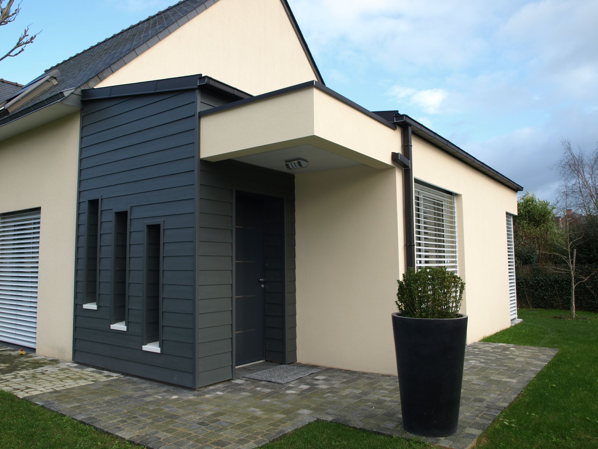 L'entrée d'une maison avec un bardage gris foncé.