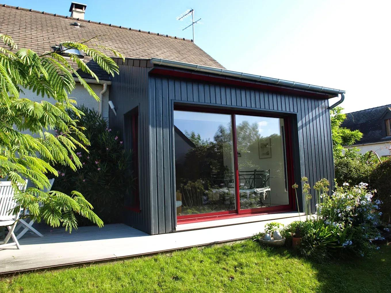 Une extension de maison avec un bardage foncé et une grande porte coulissante.