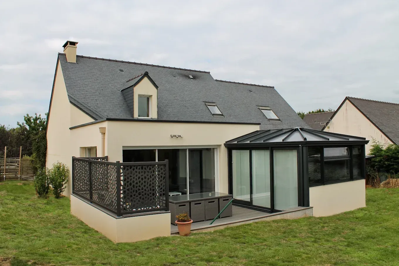 Maison avec une véranda vitrée attenante.
