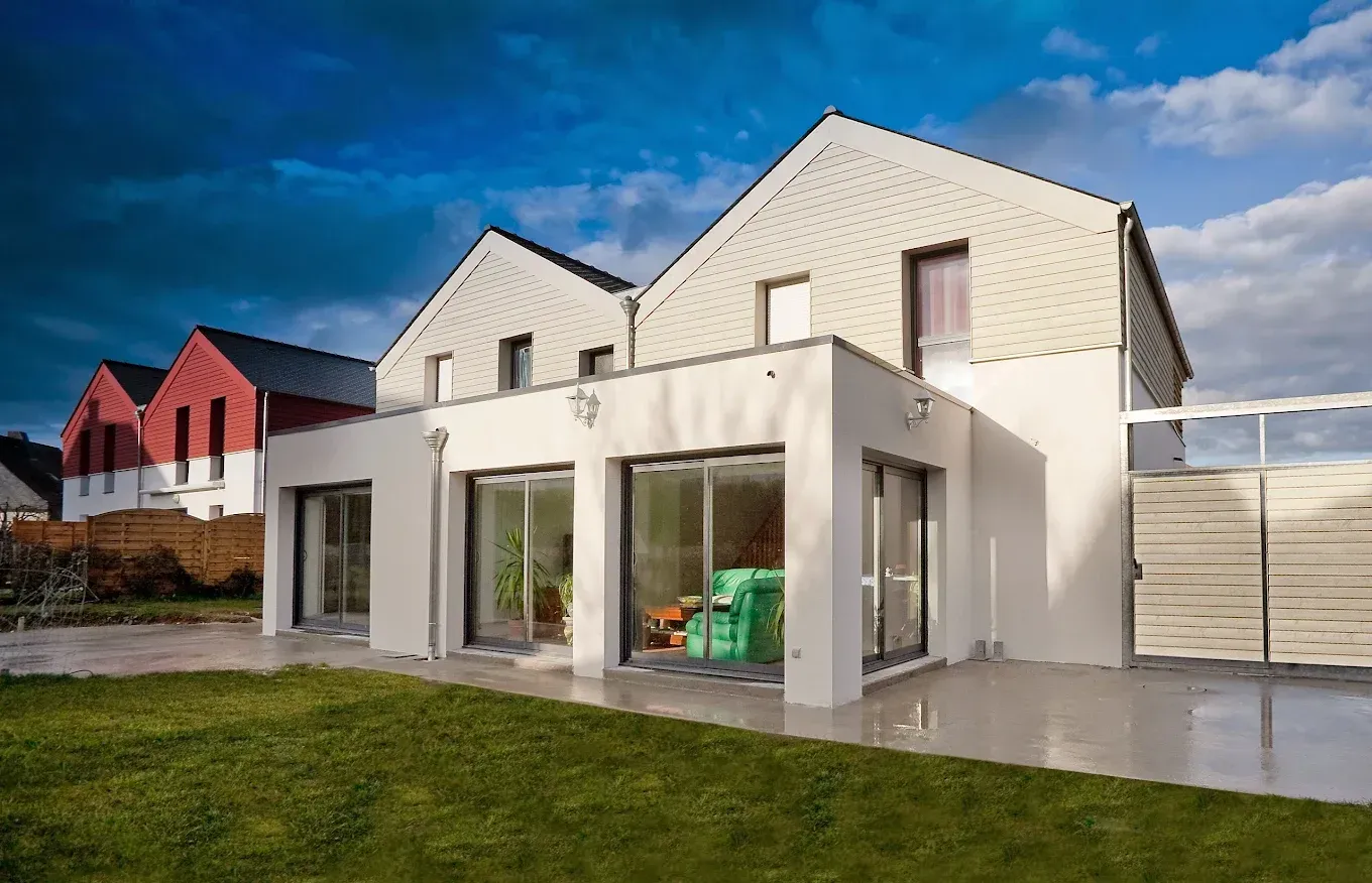 Maison avec une extension à toit plat et des portes coulissantes en verre.