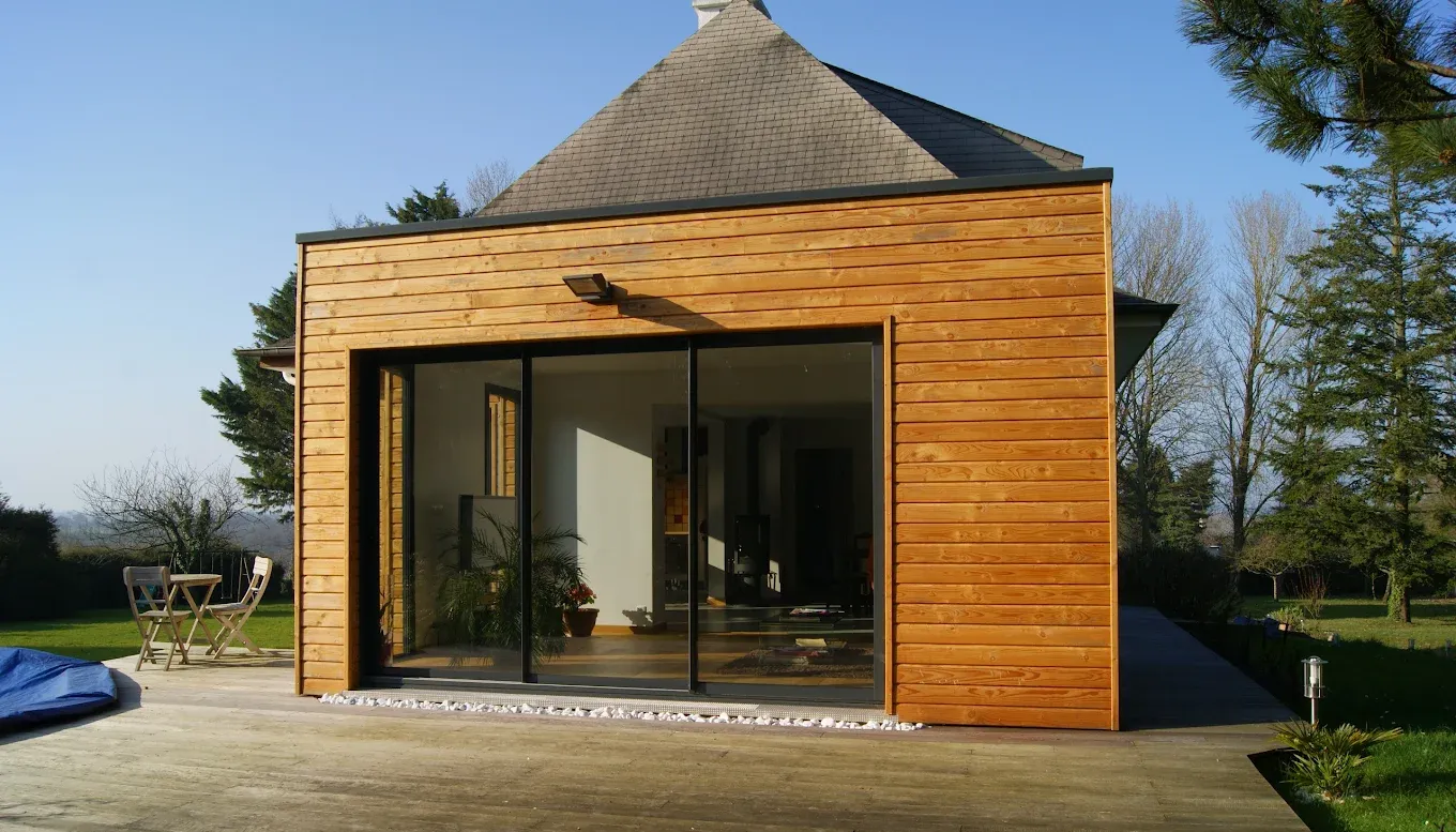 Une extension de maison en bois, dotée d'une grande porte coulissante.