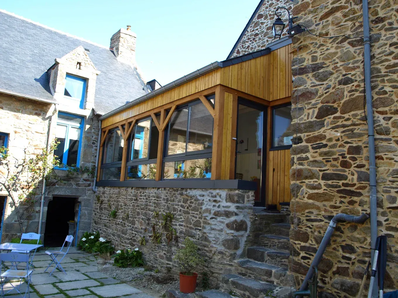Une maison en pierre agrémentée d'une extension en verre à ossature bois.