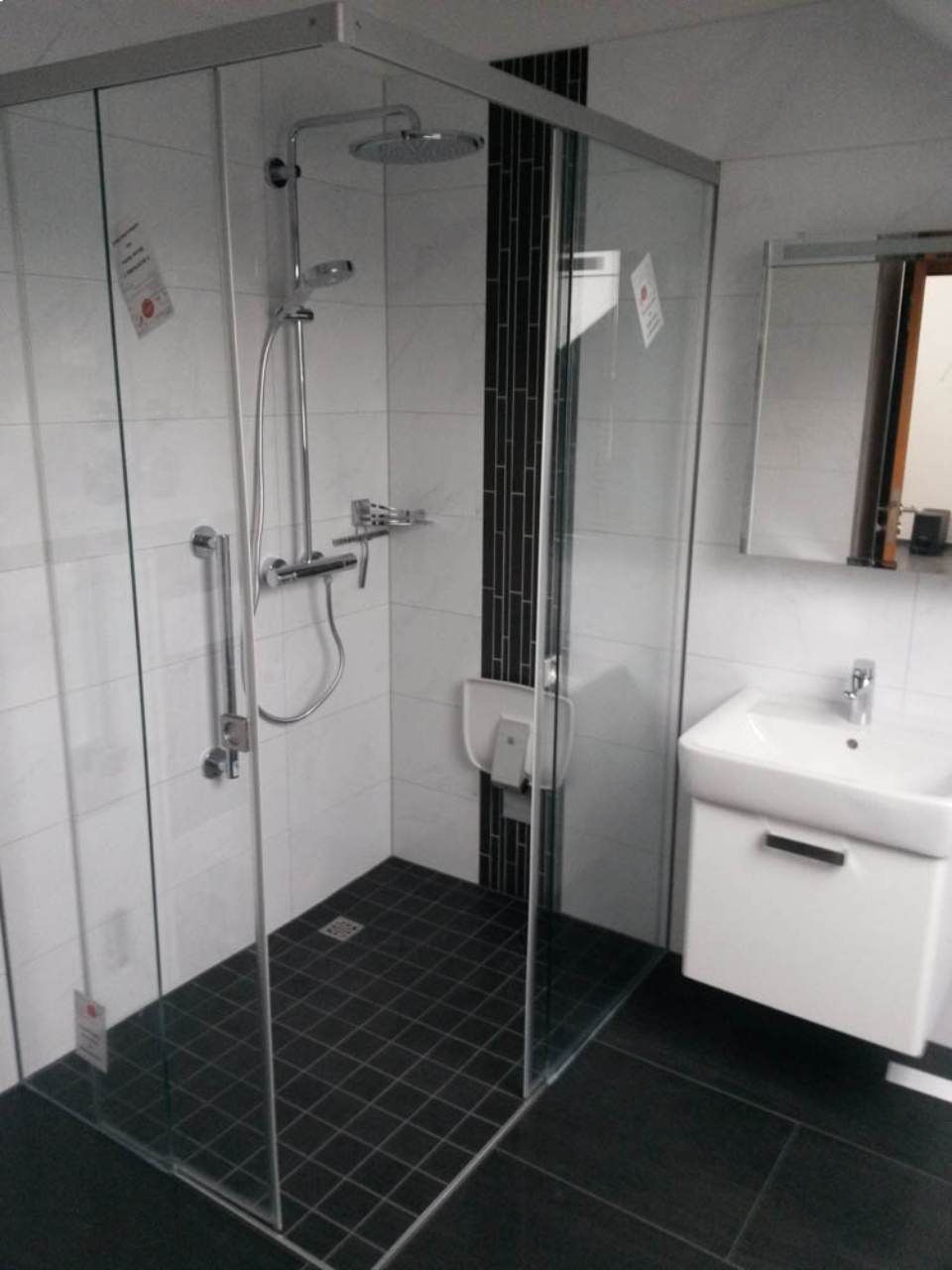 Dusche aus Glas in Badezimmer mit schwarzem Fliesenboden