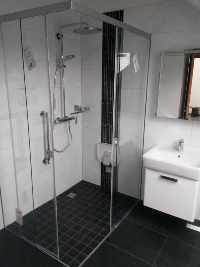 Dusche aus Glas in Badezimmer mit schwarzem Fliesenboden