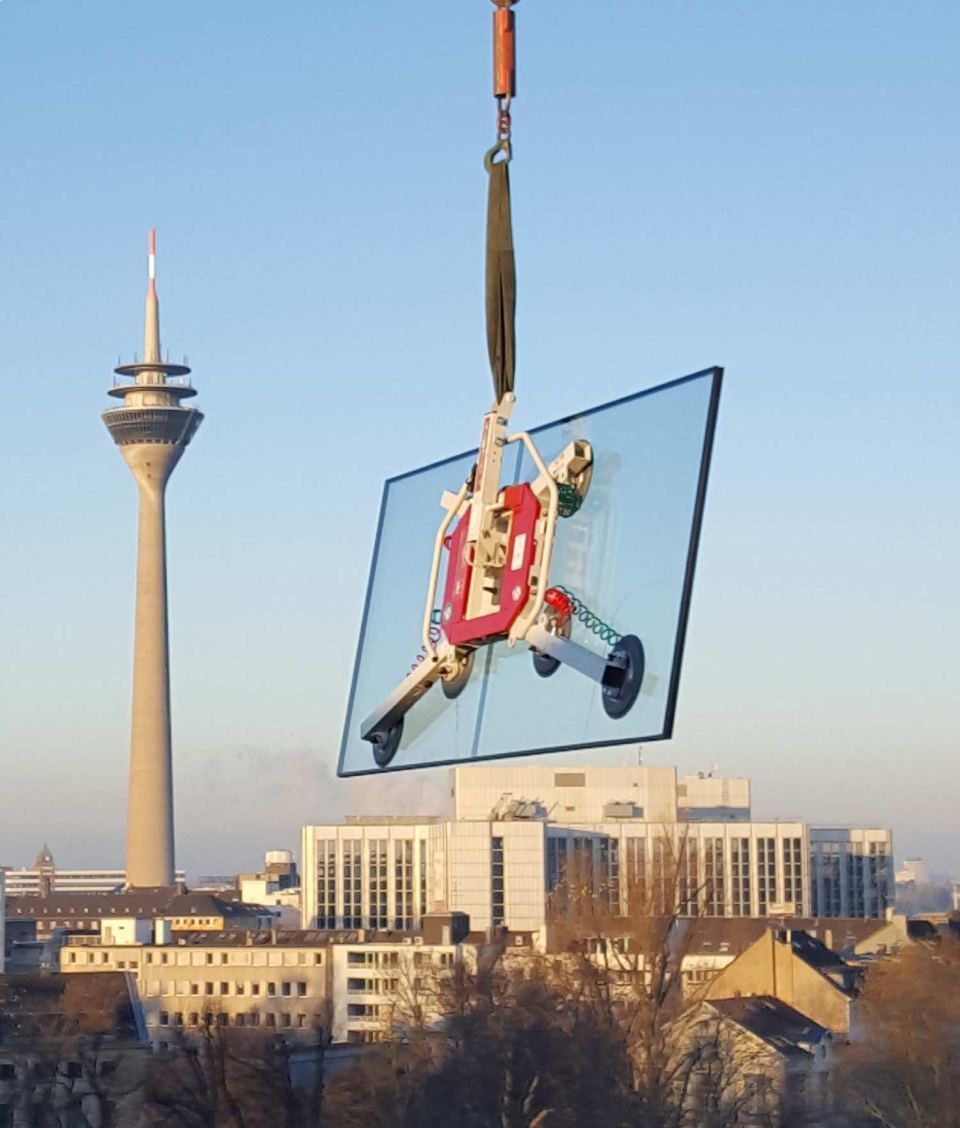Ein Schaufenster wird mit einem Kran getragen,. im Hintergrund sieht man den Rheinturm Düsseldorfs