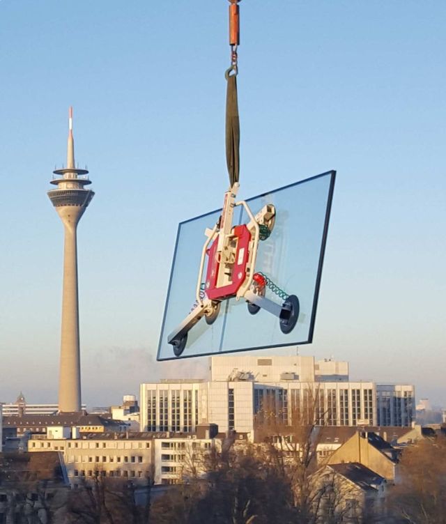 Ein Schaufenster wird mit einem Kran getragen,. im Hintergrund sieht man den Rheinturm Düsseldorfs