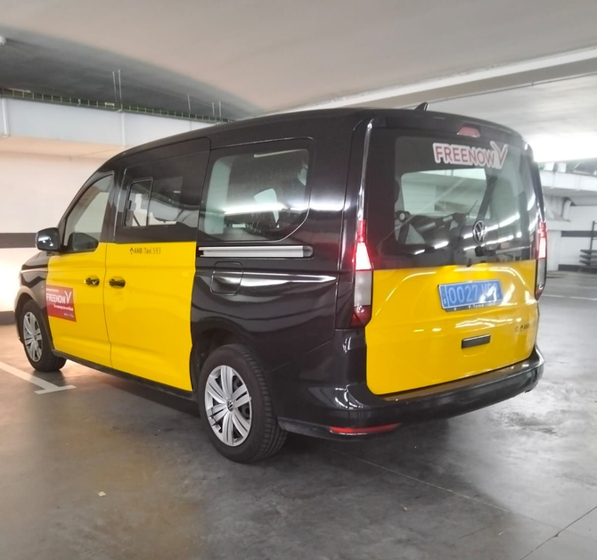 Furgoneta taxi amarilla y negra en un estacionamiento.