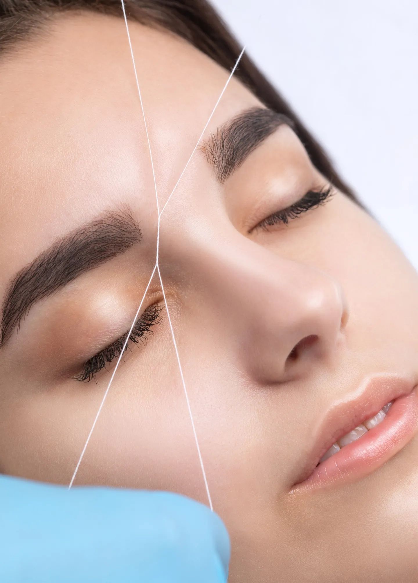 Una mujer se está depilando las cejas con hilo en un salón de belleza.