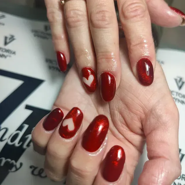 Un primer plano de las manos de una mujer con uñas rojas y un corazón en ellas.