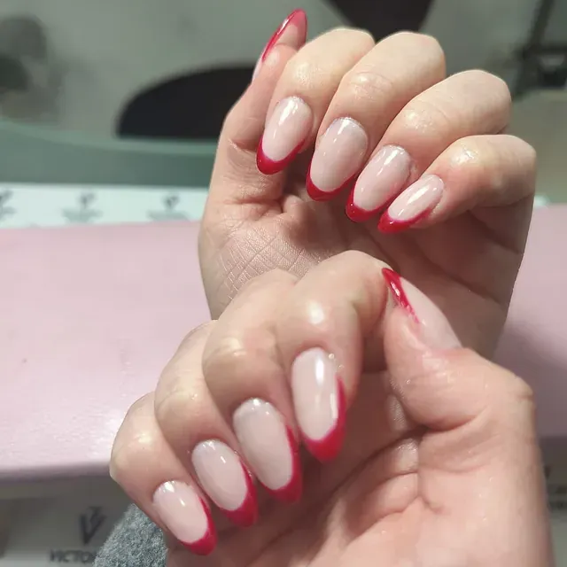 Un primer plano de las uñas de una mujer con una manicura francesa roja.