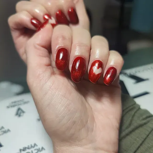 Un primer plano de la mano de una persona con uñas rojas.