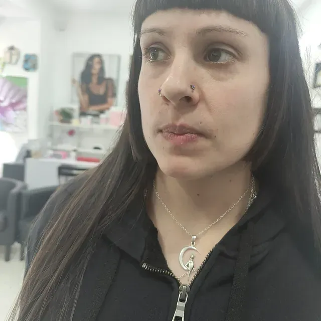 Una mujer que lleva un anillo en la nariz y un collar con la letra g.