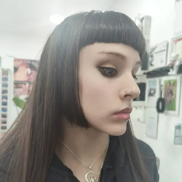 Una mujer con pelo largo y flequillo lleva un collar.