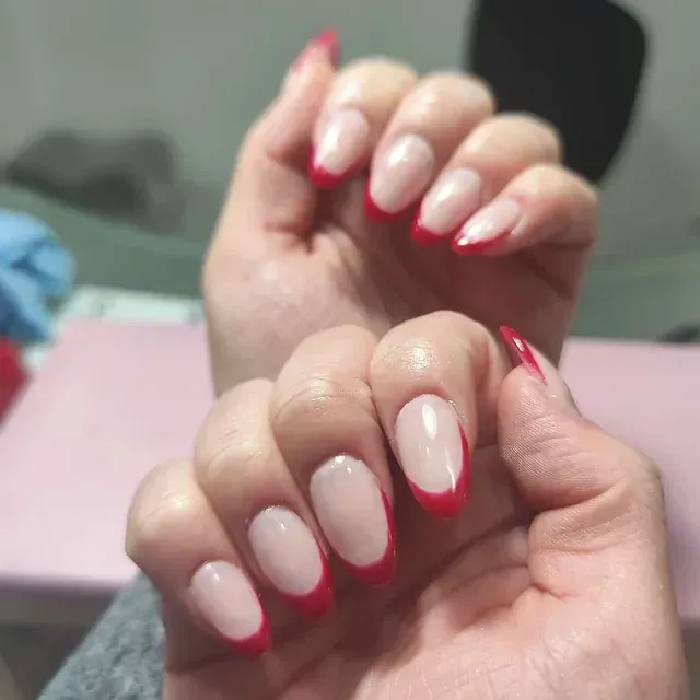 Un primer plano de las uñas de una mujer con una manicura francesa roja.