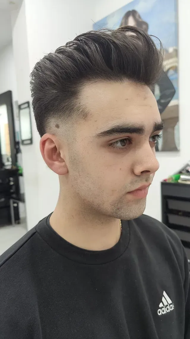 Un joven que viste una sudadera adidas negra se está cortando el pelo.