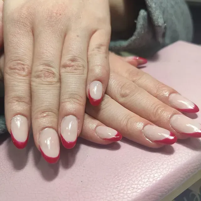 Un primer plano de las uñas de una mujer con una manicura francesa roja.