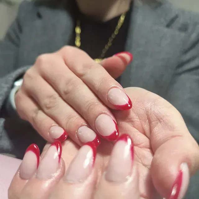 Un primer plano de la mano de una mujer con uñas rojas.