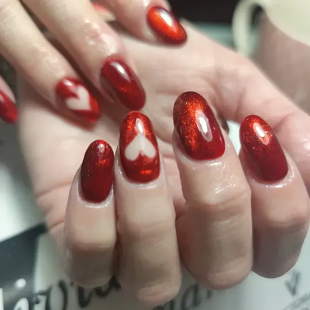 Un primer plano de las uñas rojas de una mujer con un corazón en ellas.