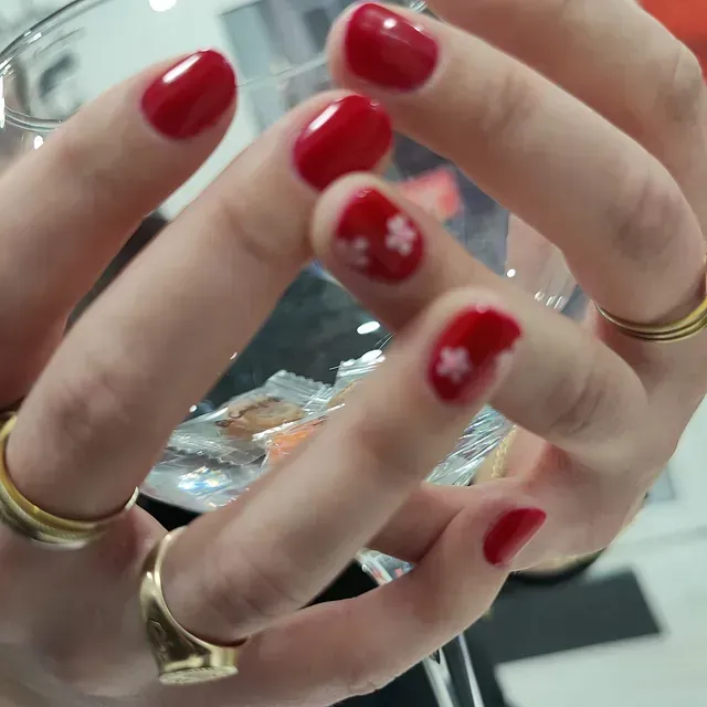 Una mujer con uñas rojas sostiene una copa de vino.