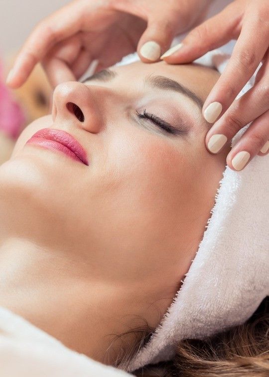 Una mujer está recibiendo un masaje facial en un spa.