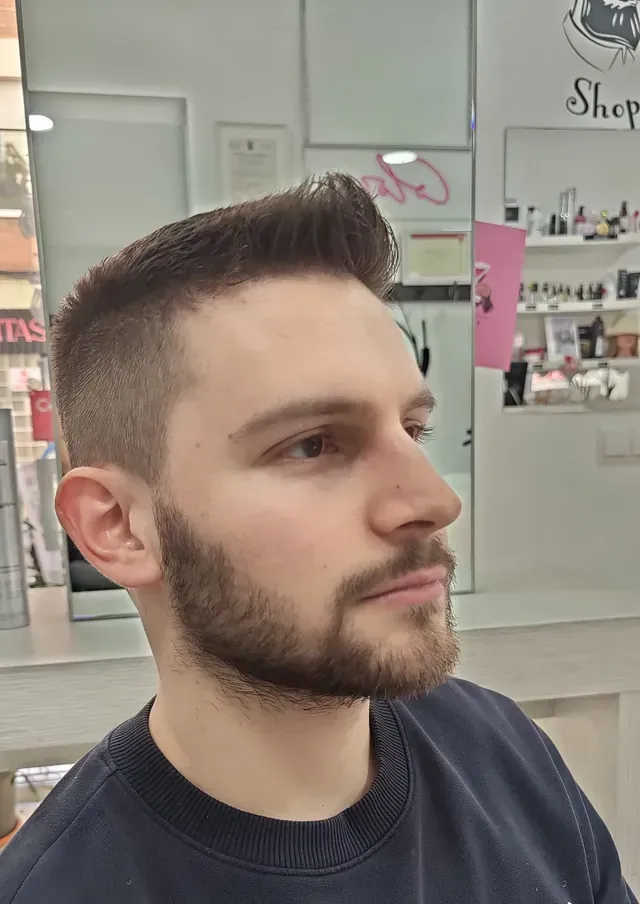Un hombre con barba se está cortando el pelo en una peluquería.