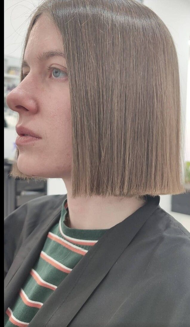 Una mujer con pelo corto lleva una camisa de rayas y una chaqueta negra.