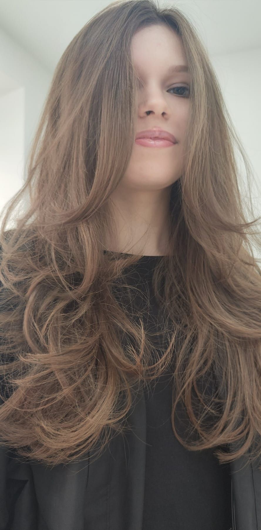 Una mujer con cabello largo y castaño lleva una camisa negra.