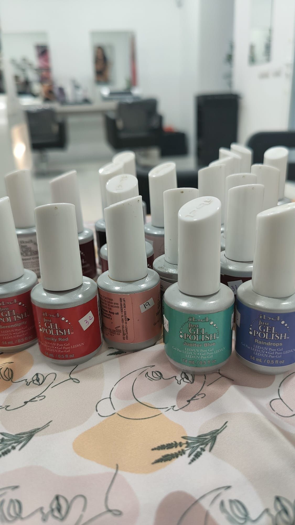 Un montón de botellas de esmalte de uñas están sobre una mesa.