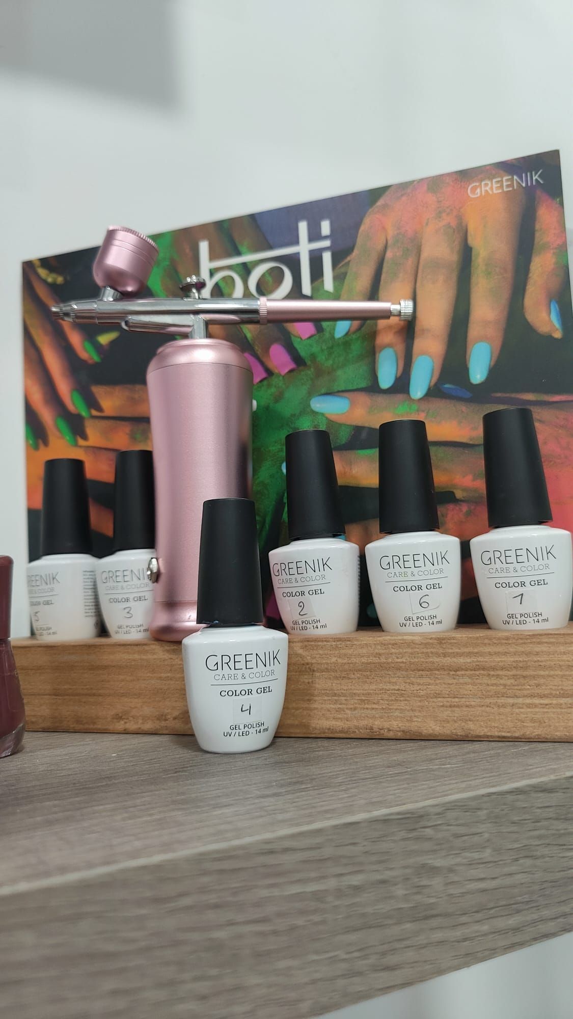 Un estante con botellas de esmalte de uñas y un aerógrafo encima.