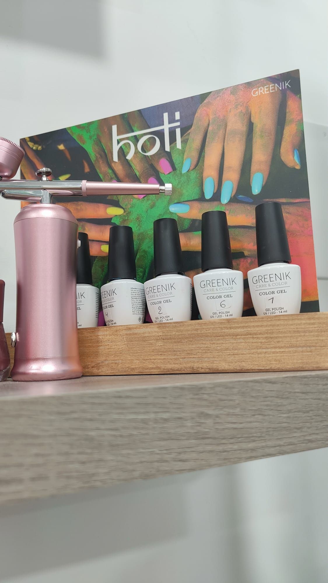 Un estante con botellas de esmalte de uñas y un aerógrafo encima.