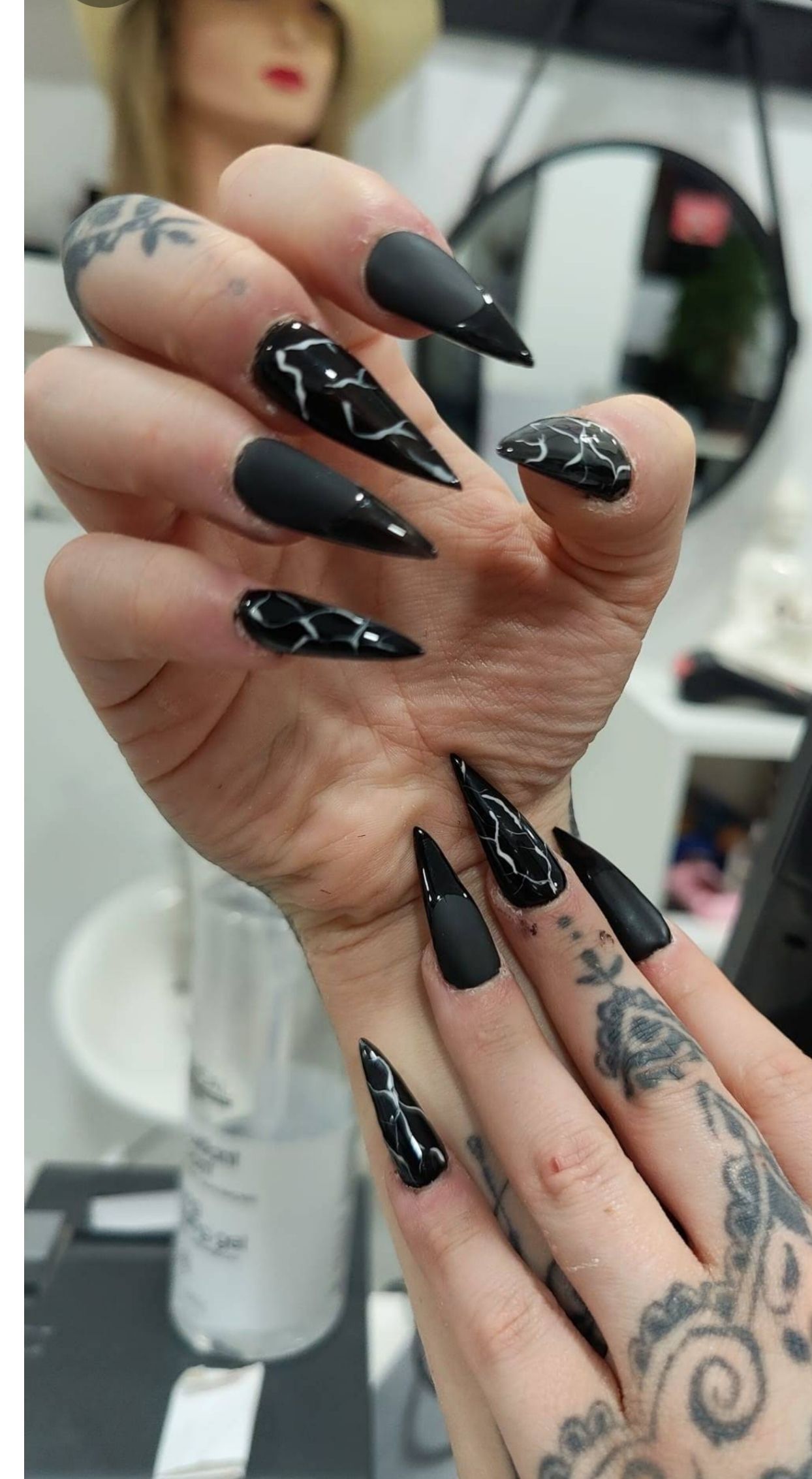 Un primer plano de la mano de una mujer con largas uñas negras.