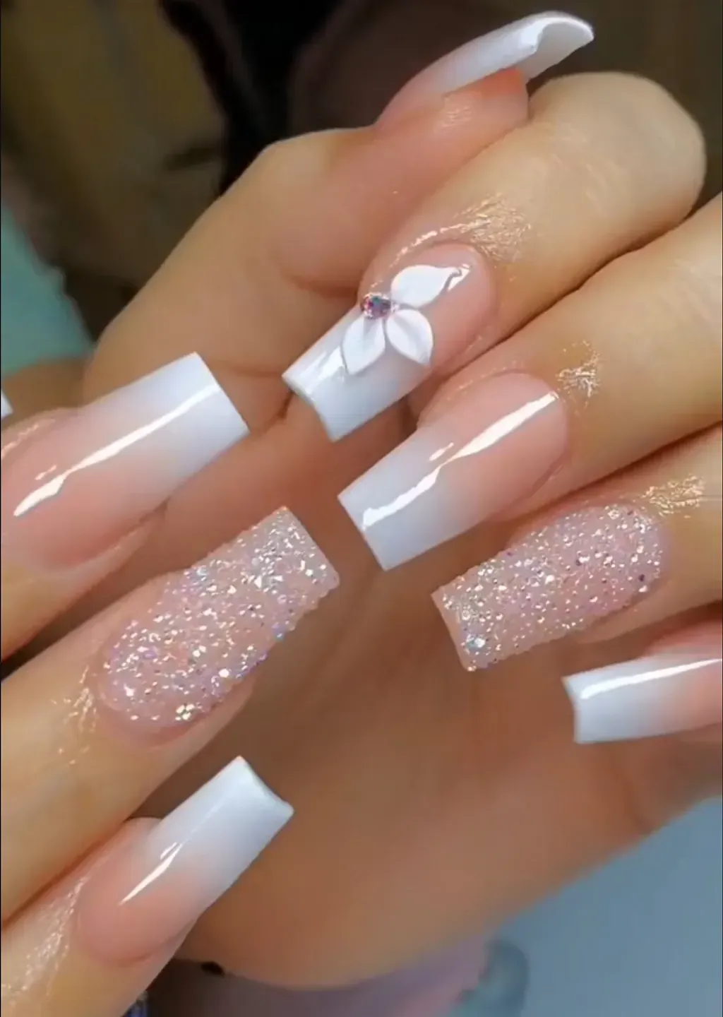 Un primer plano de las uñas de una persona con una flor en ellas.