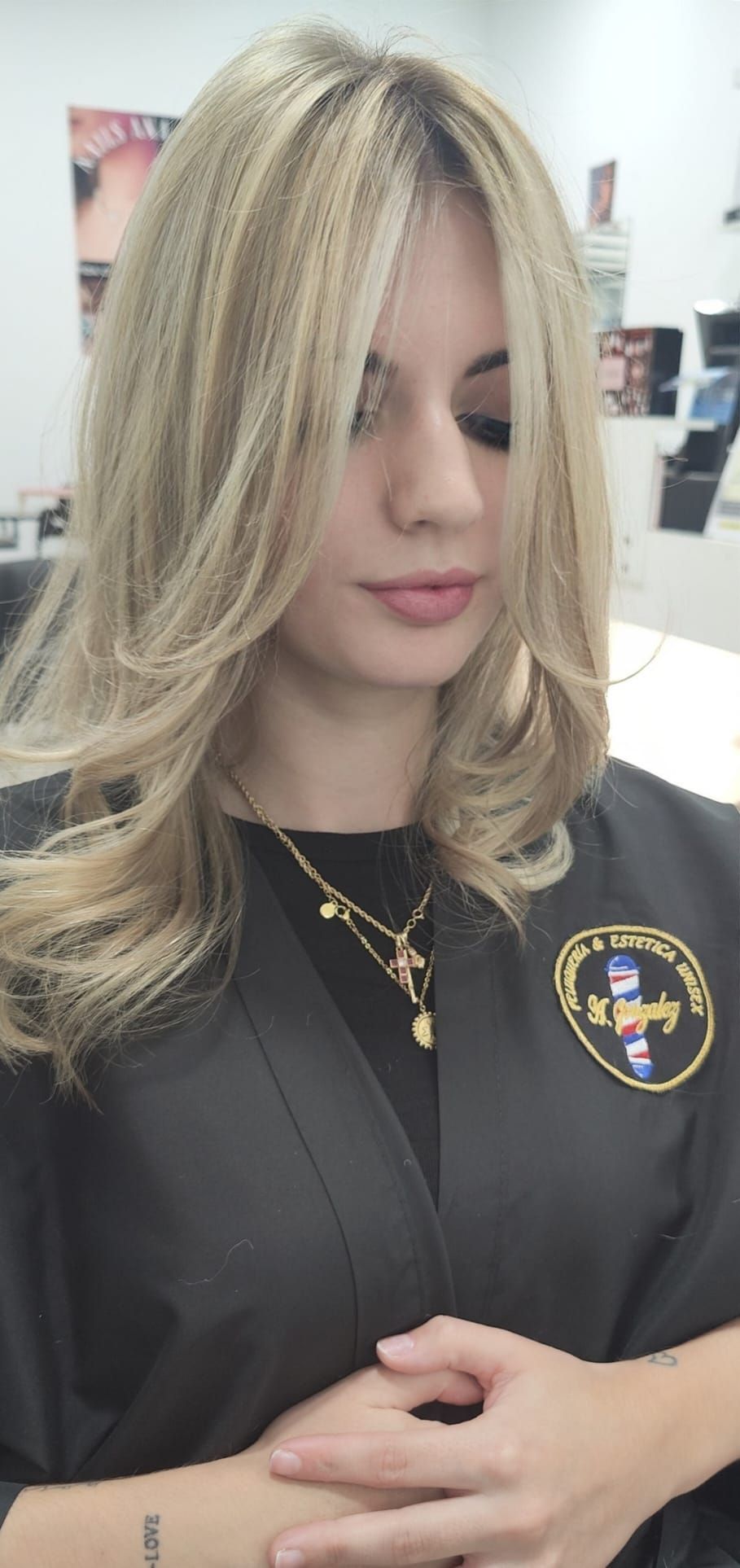 Una mujer con cabello largo y rubio está sentada en una silla en un salón.