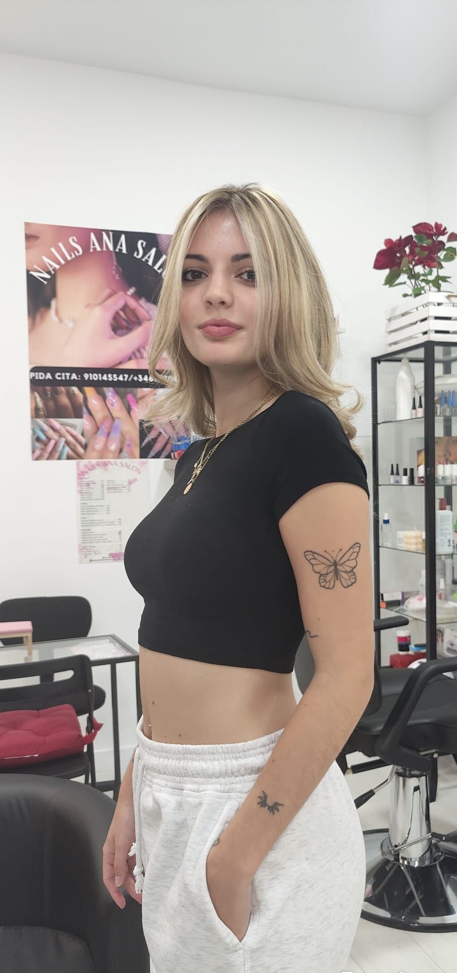 Una mujer con un tatuaje en el brazo está parada en un salón.