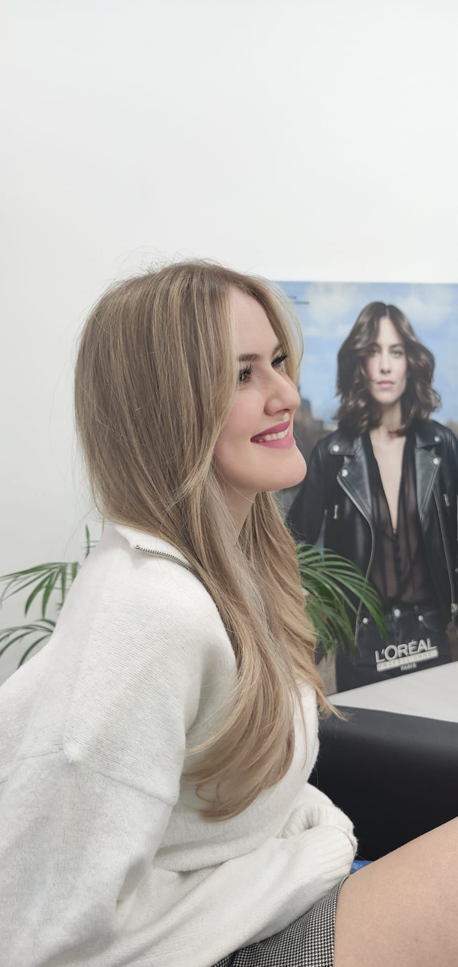 Una mujer está sentada delante de un cuadro de una mujer.