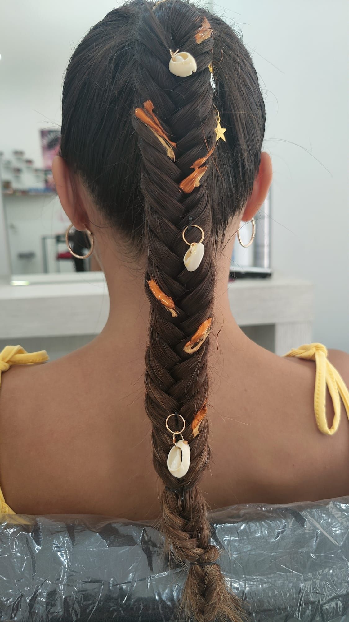 Una mujer está sentada en una bañera con el cabello recogido en una trenza.