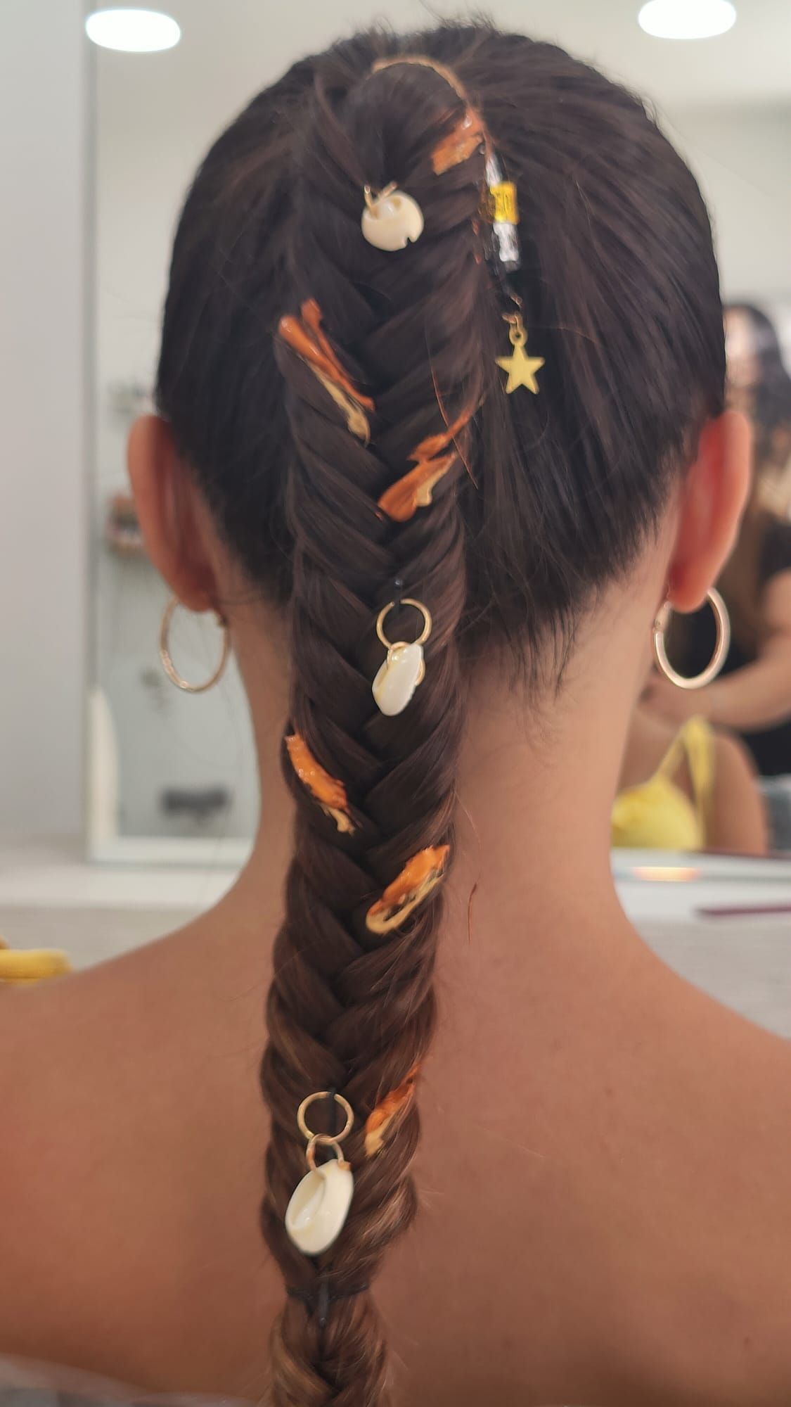 La parte posterior de la cabeza de una mujer con una trenza y pendientes.