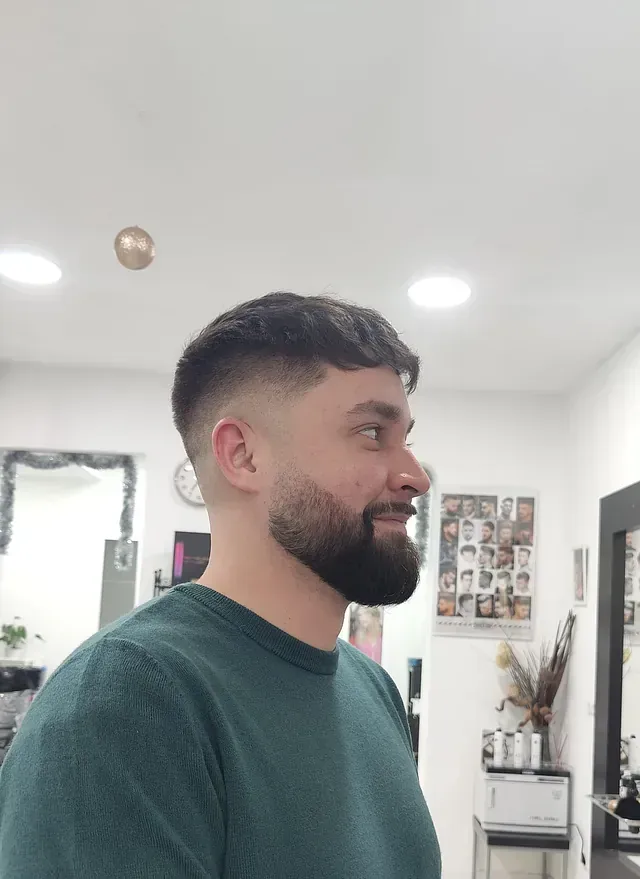 Un hombre con barba lleva una camisa verde.