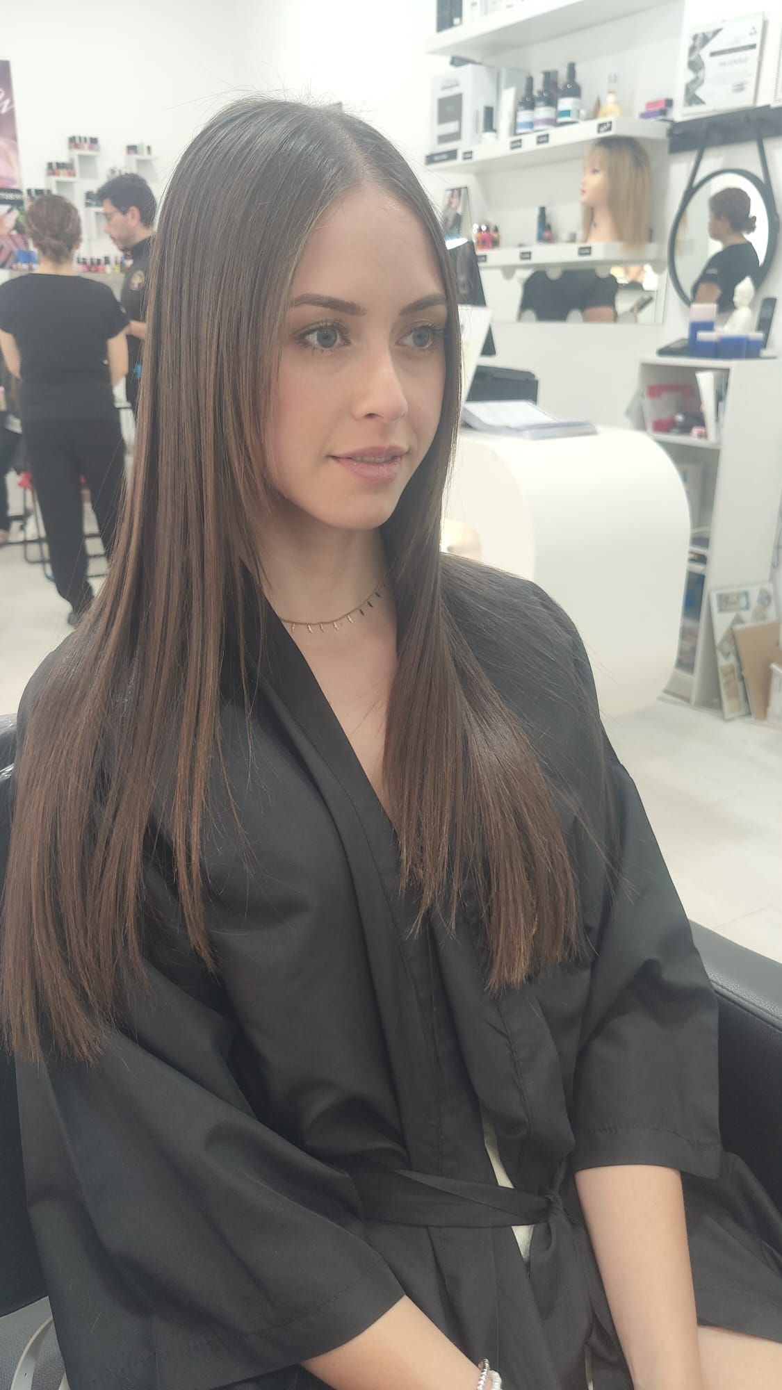 Una mujer con una túnica negra está sentada en una silla en un salón.