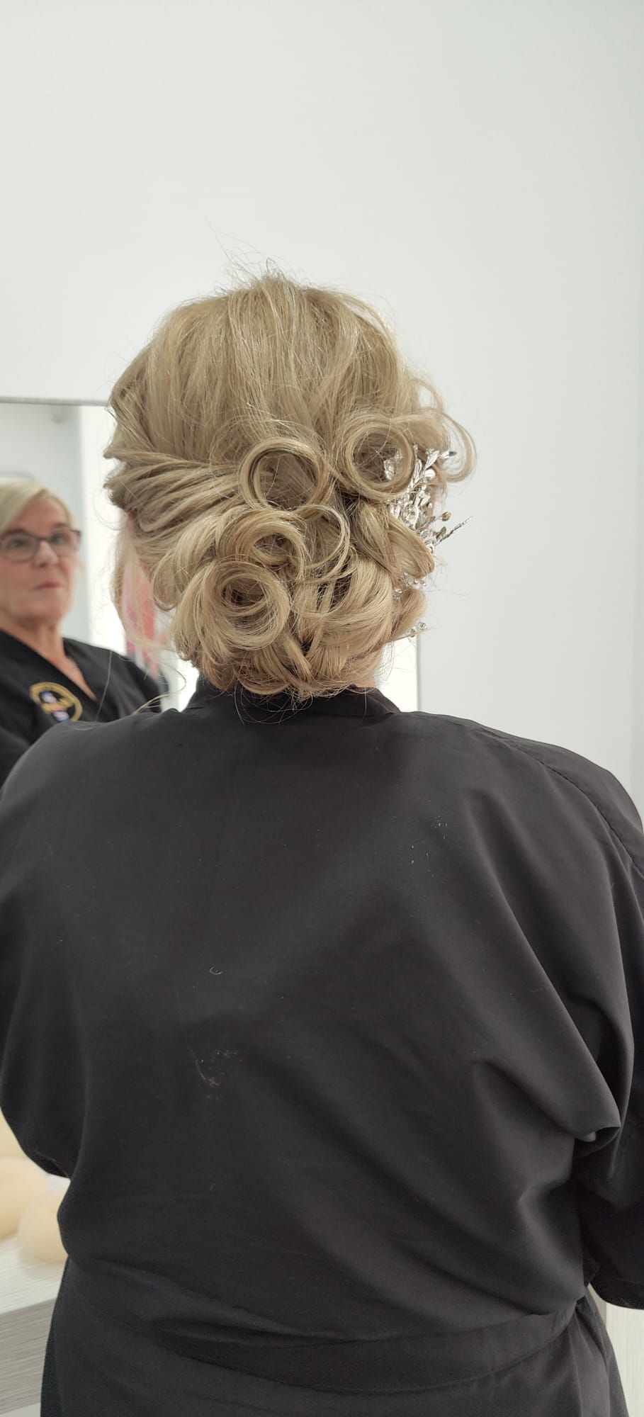 Una mujer está parada frente a un espejo con el cabello recogido en un moño.